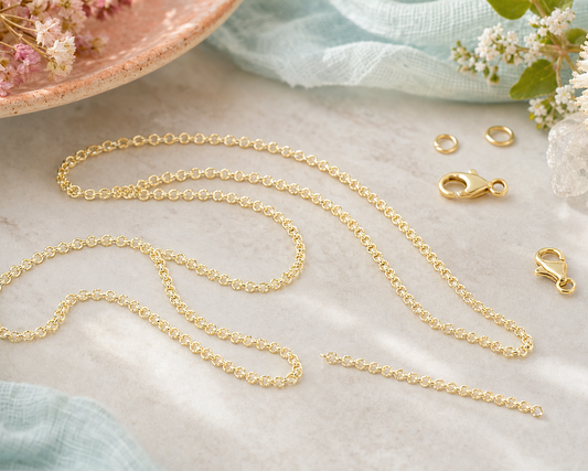 Length of fine gold rolo chain with round interlocking links, coiled on a pale surface