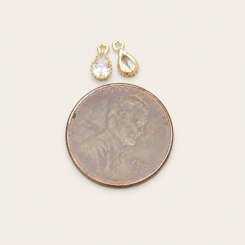 Small teardrop framed glass pendant with a textured bezel and top loop