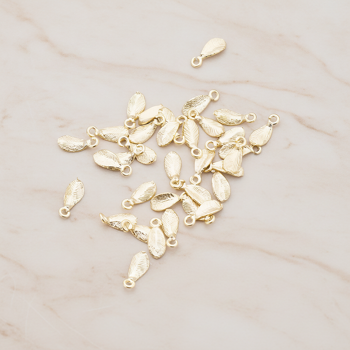 Tiny Leaf Charm Pendant, 8 Pc on warm marble background (PD.426)